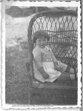Retrato de una niña sentada en un asiento de mimbre